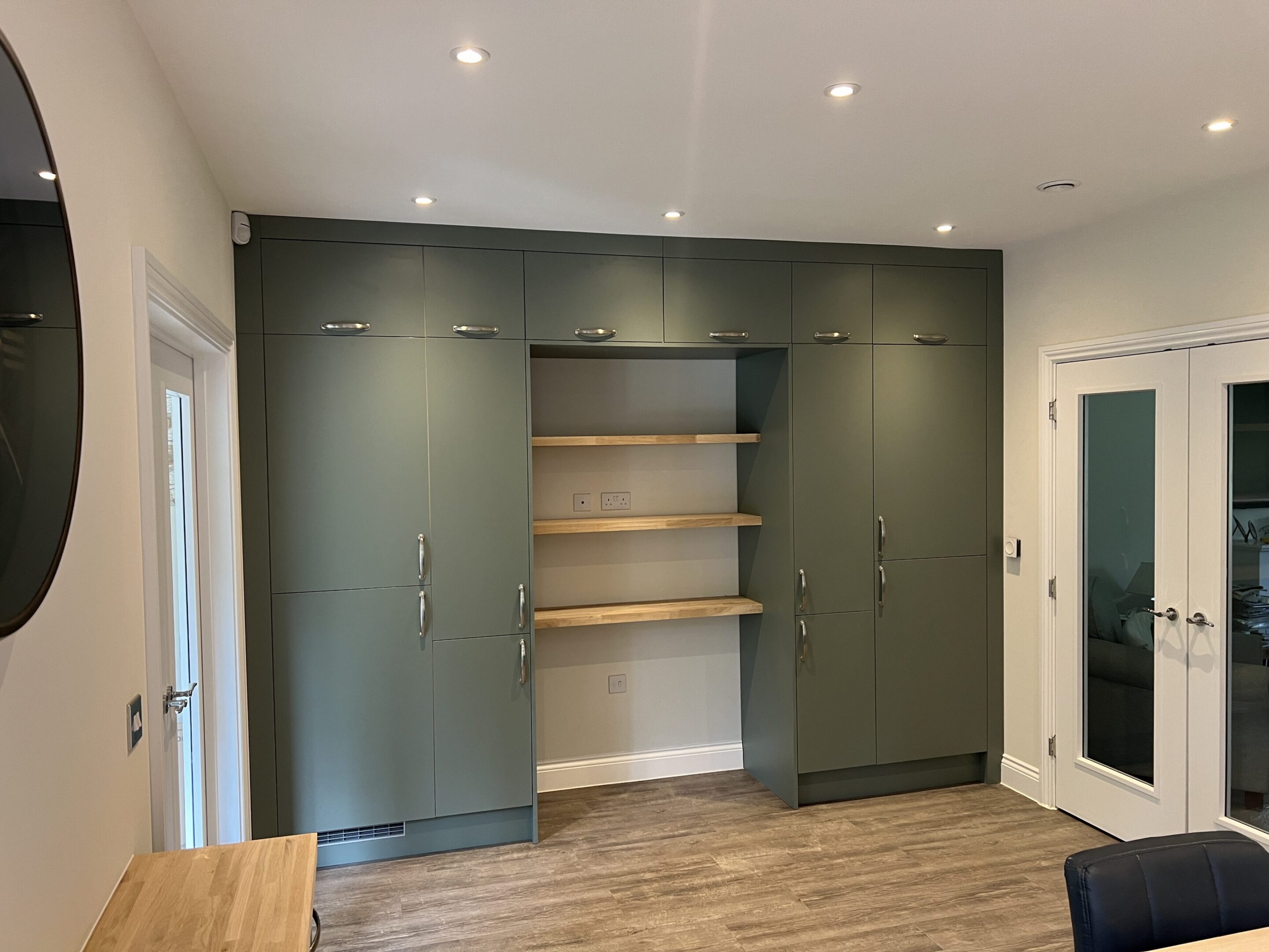 Built-in green cabinets with wooden open shelves