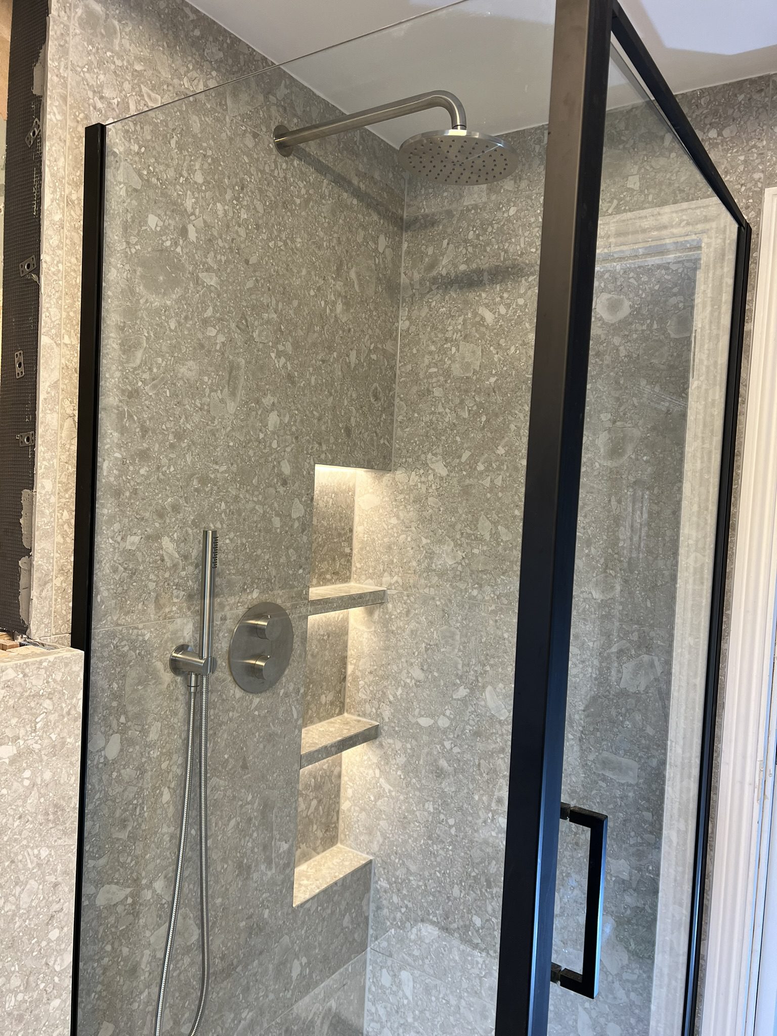 Gray stone shower with illuminated recessed shelves