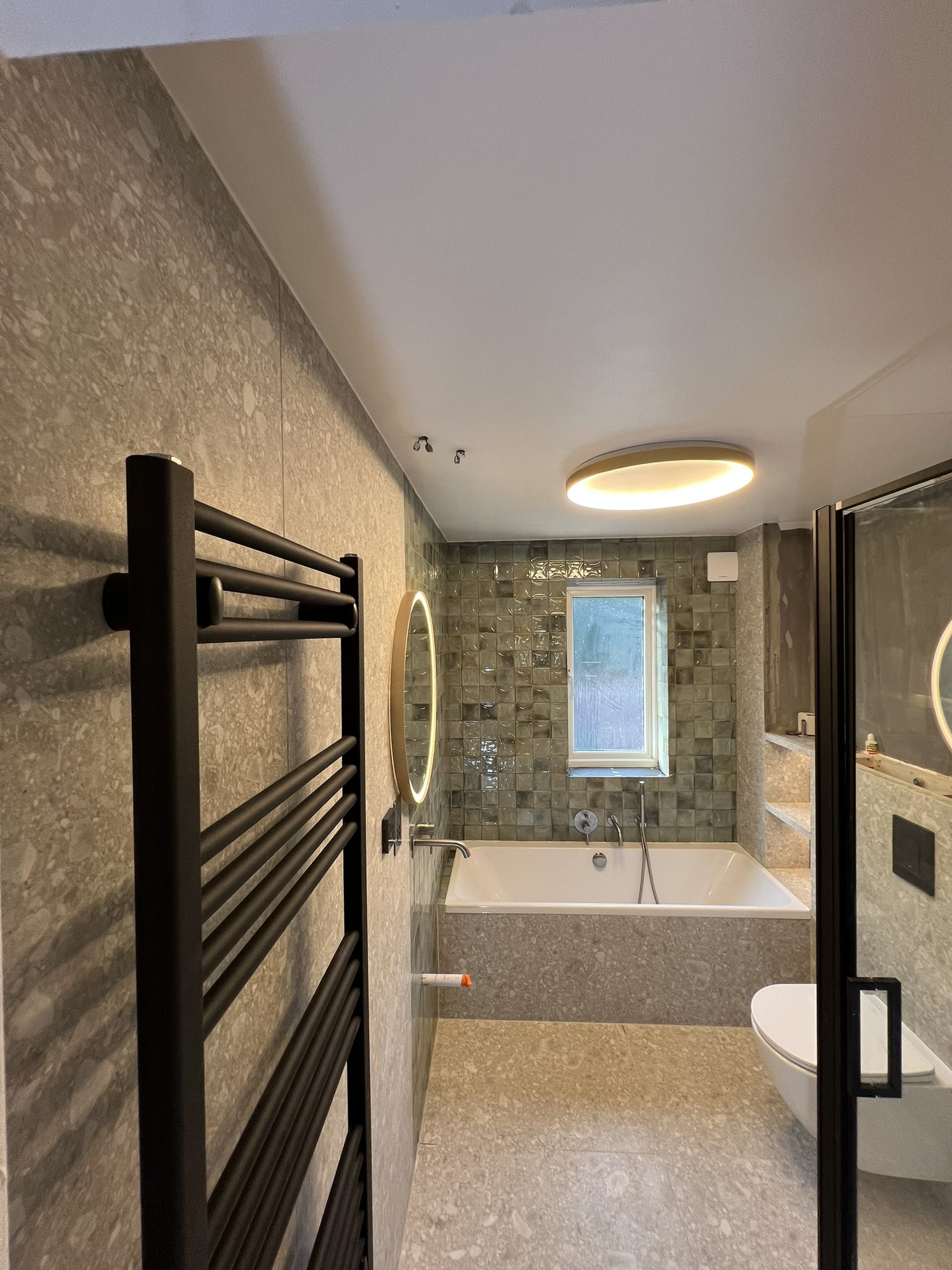 Modern tiled bathroom with bathtub and mirror
