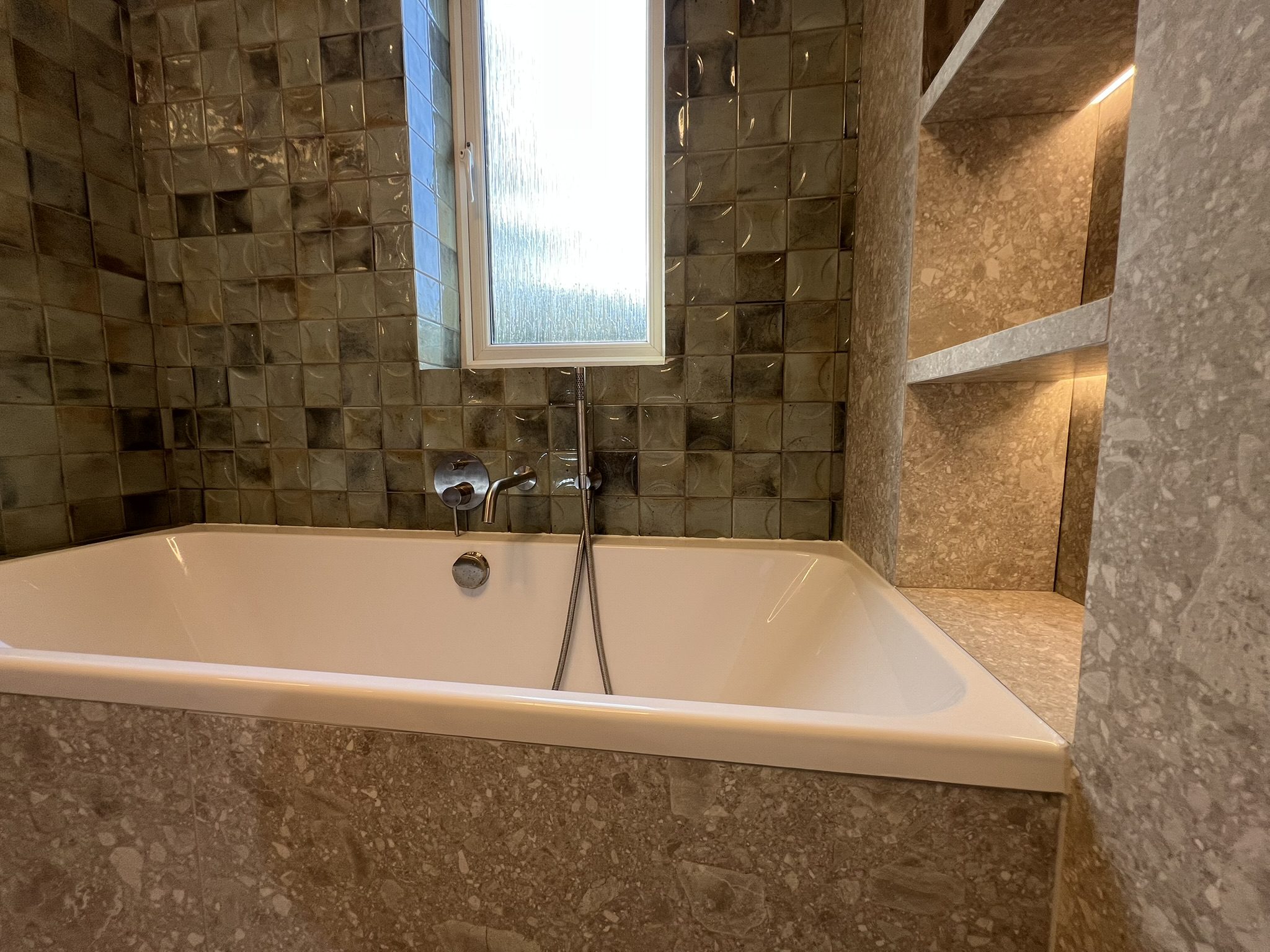 Modern bathtub with textured tile and window