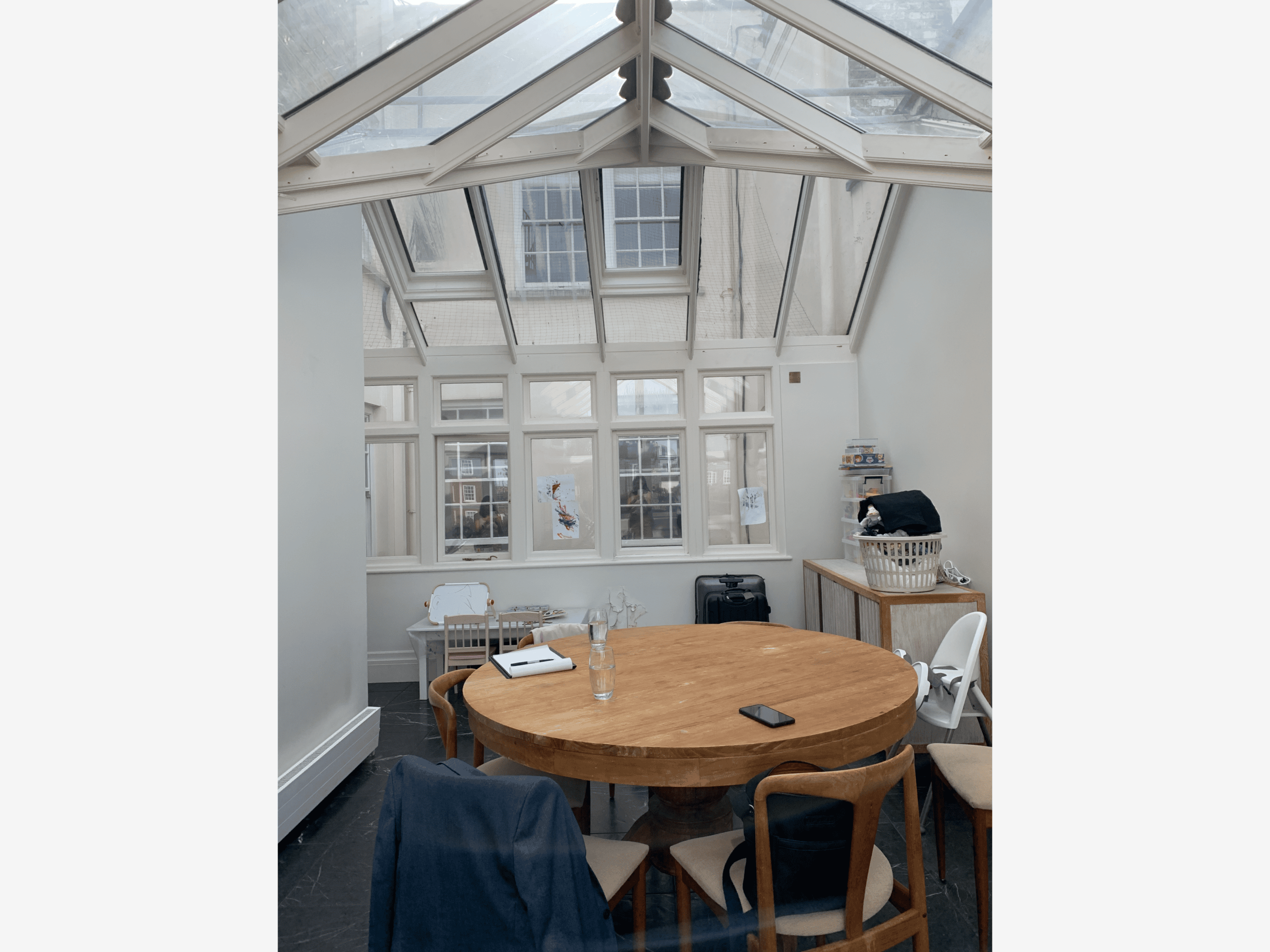 Sunlit conservatory with round wooden dining table