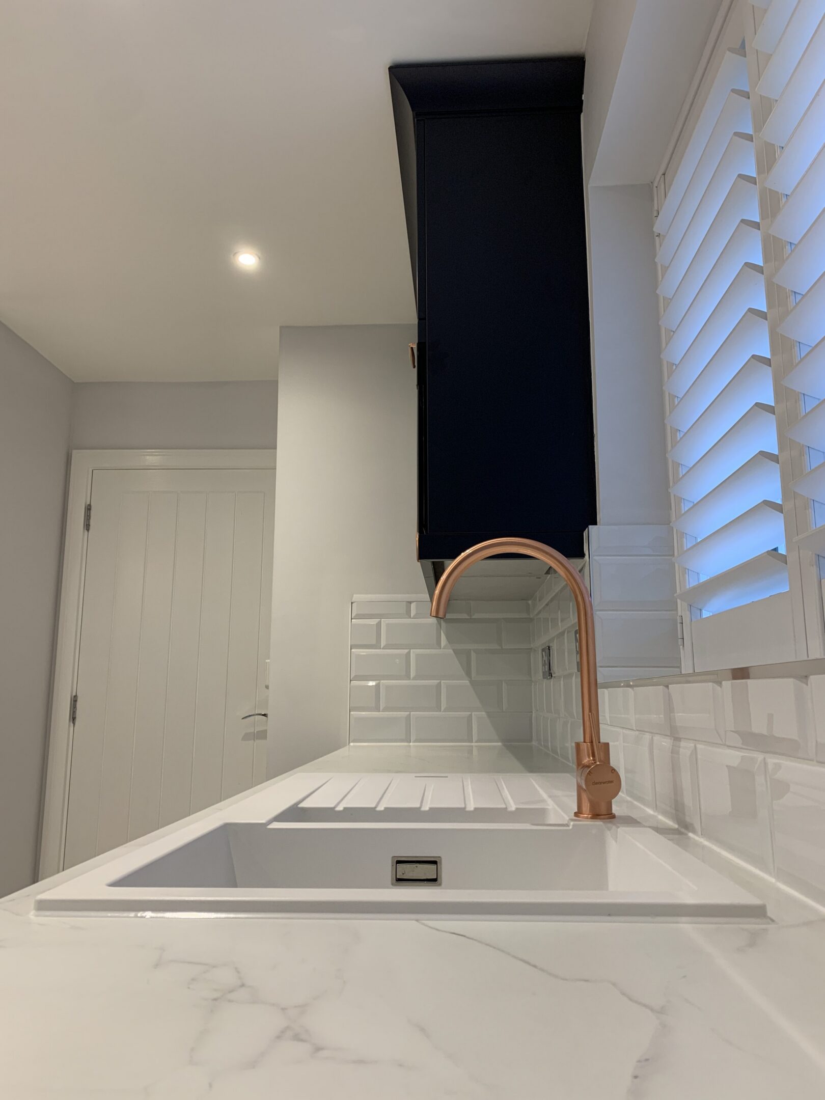White sink with copper faucet and subway tile