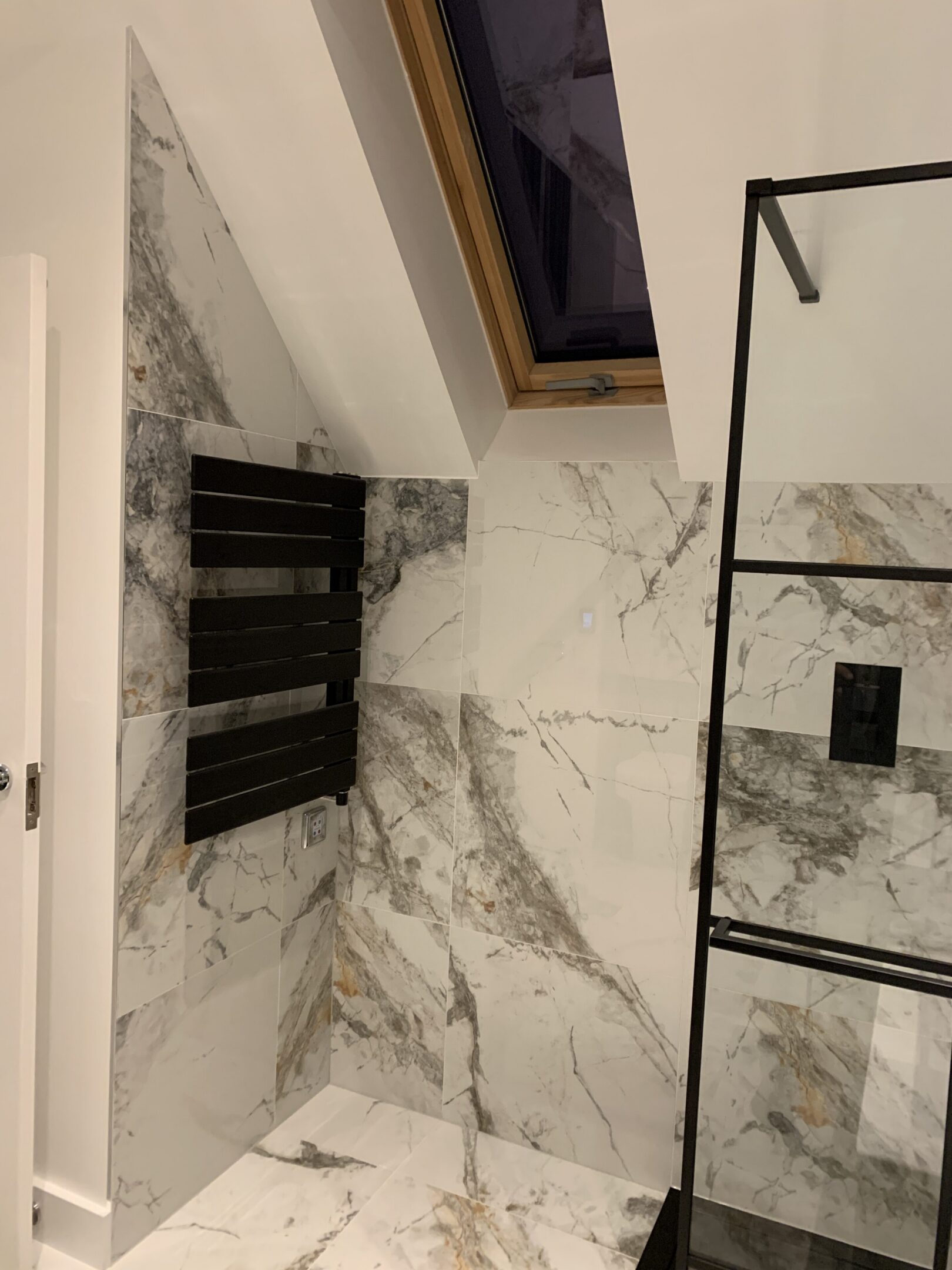 Modern marble bathroom with skylight and radiator