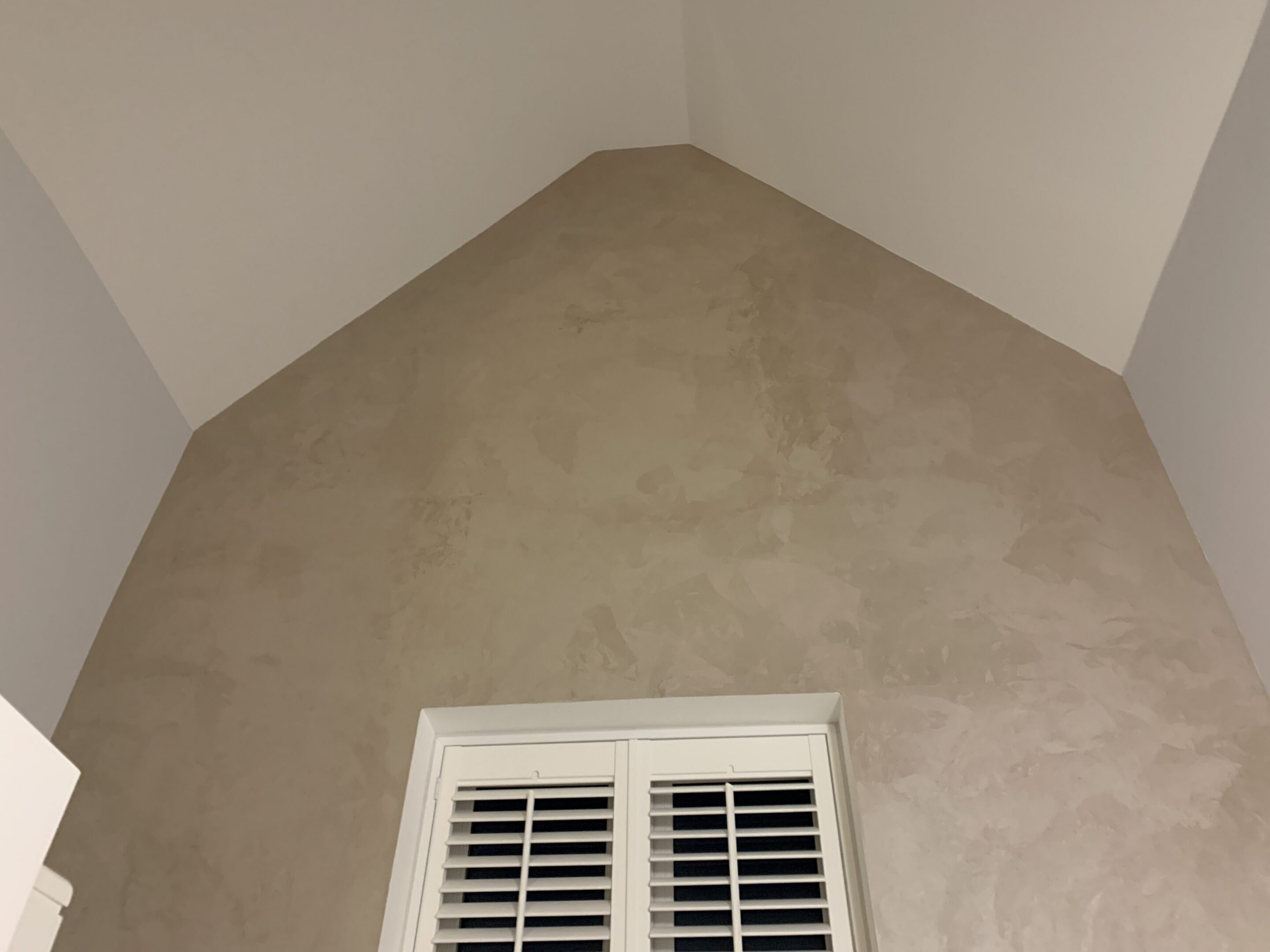 Vaulted beige wall with window shutters