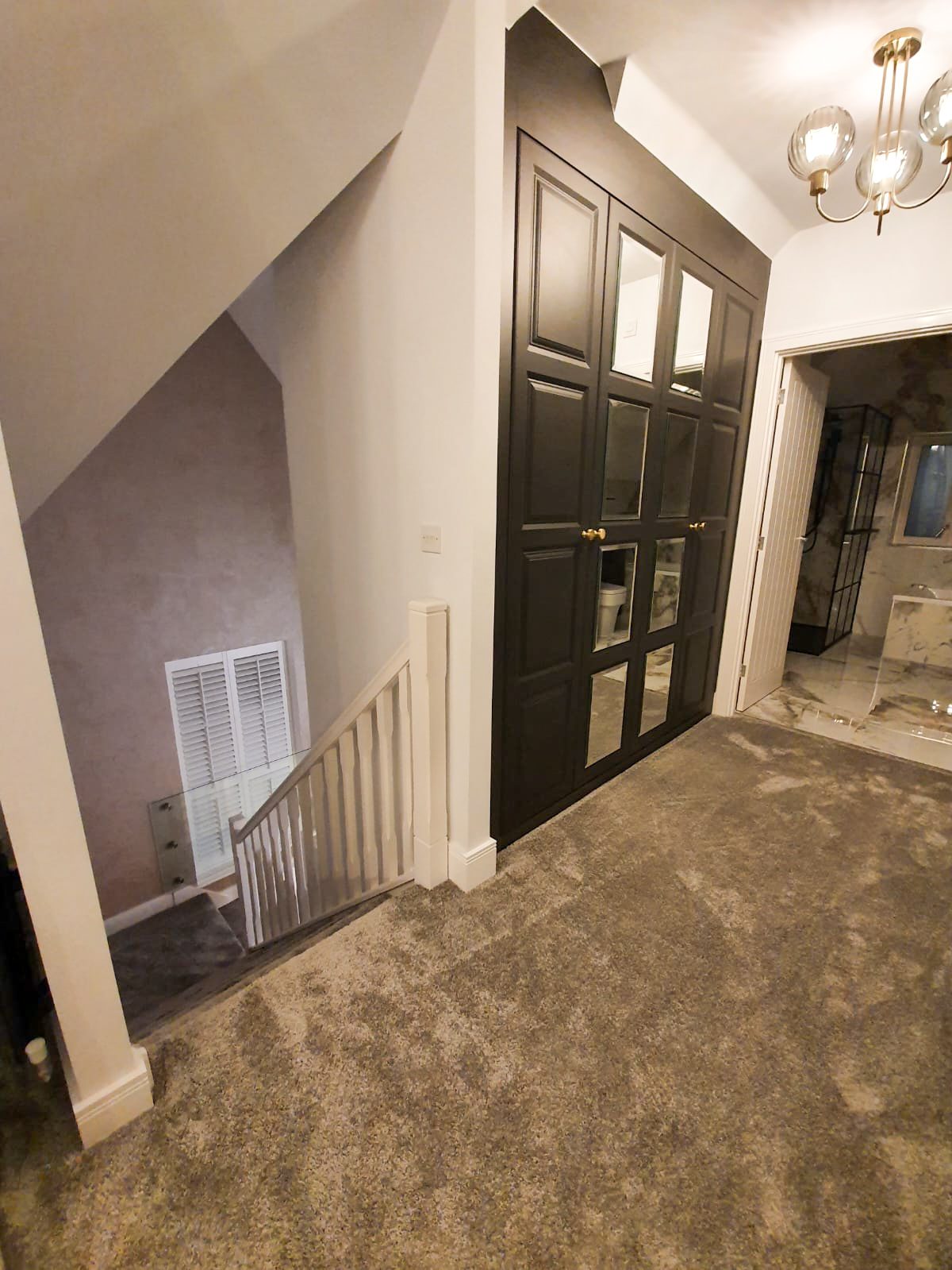 Carpeted upstairs hallway with dark paneled doors