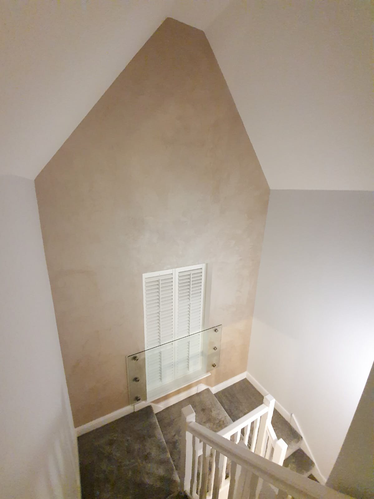 Staircase with triangular wall and glass railing
