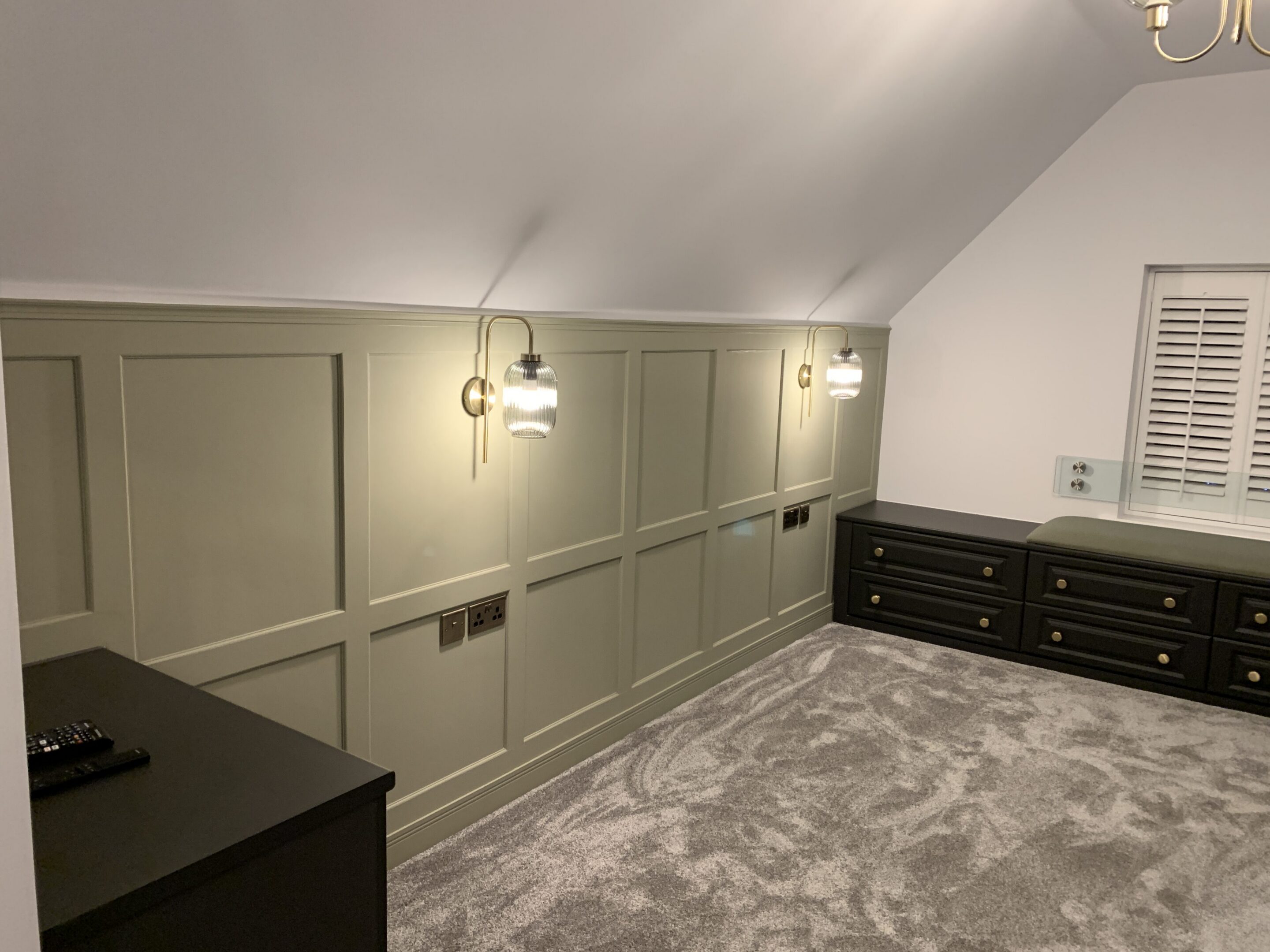 Attic room with green paneled wall and sconces