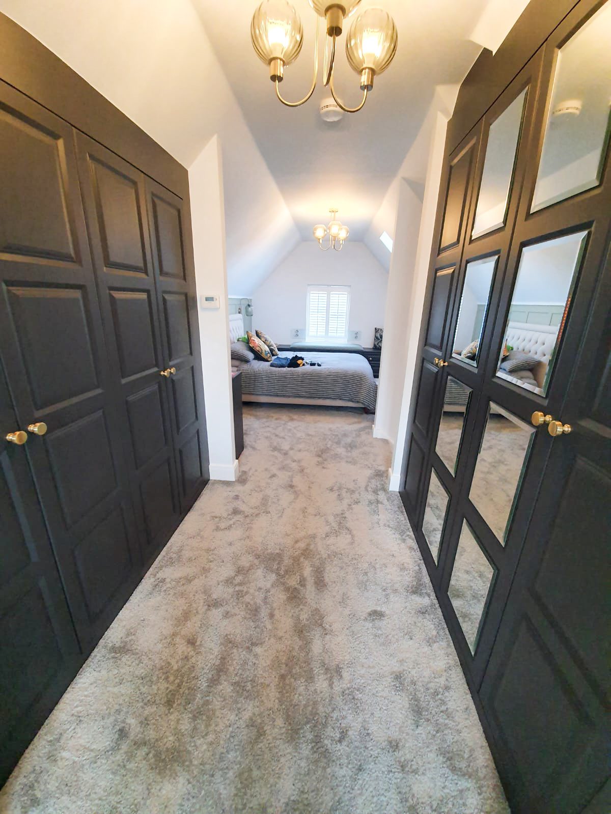 Carpeted hallway with mirrored wardrobes and bedroom