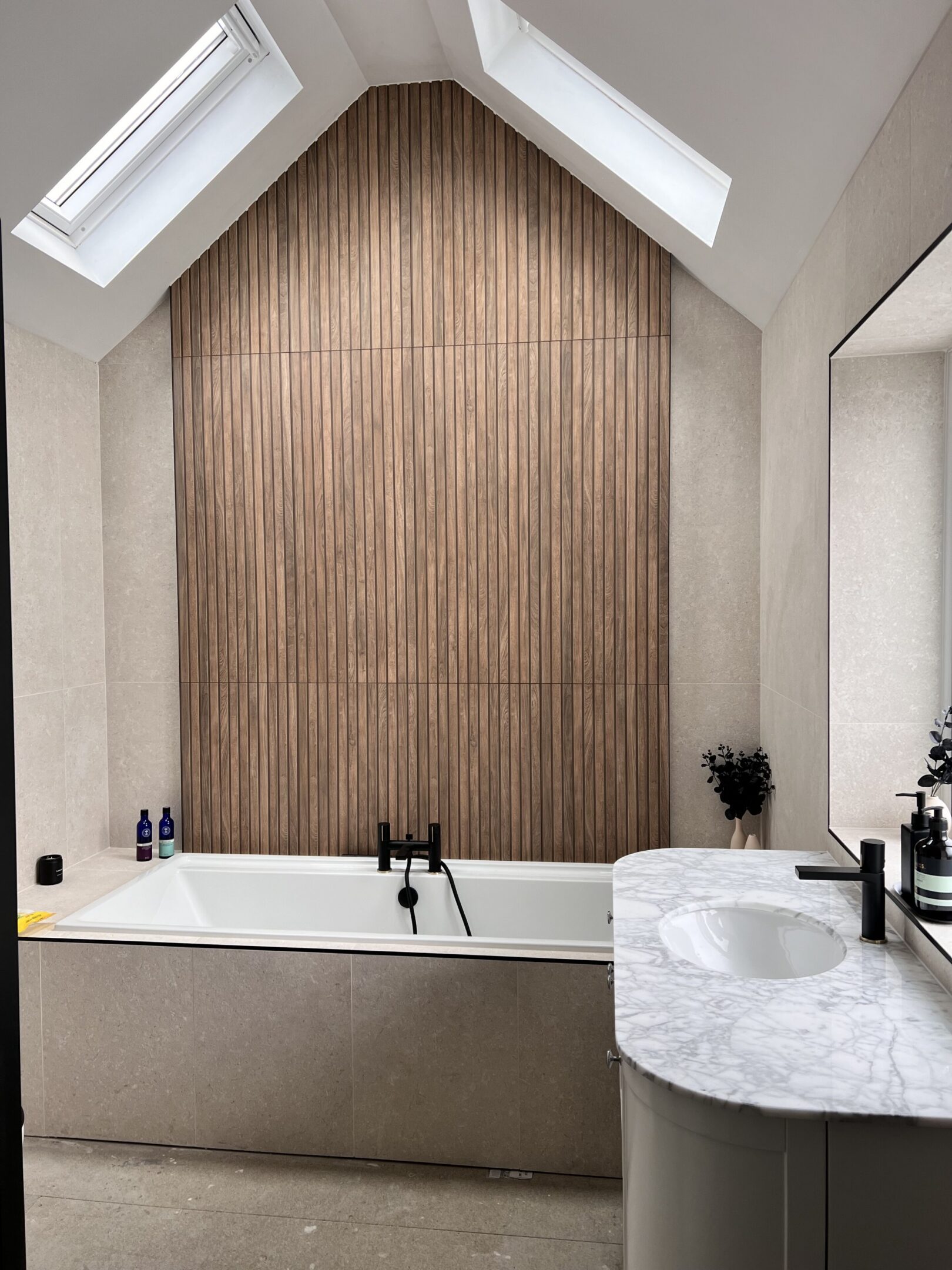 Bathtub under skylights with wood accent wall
