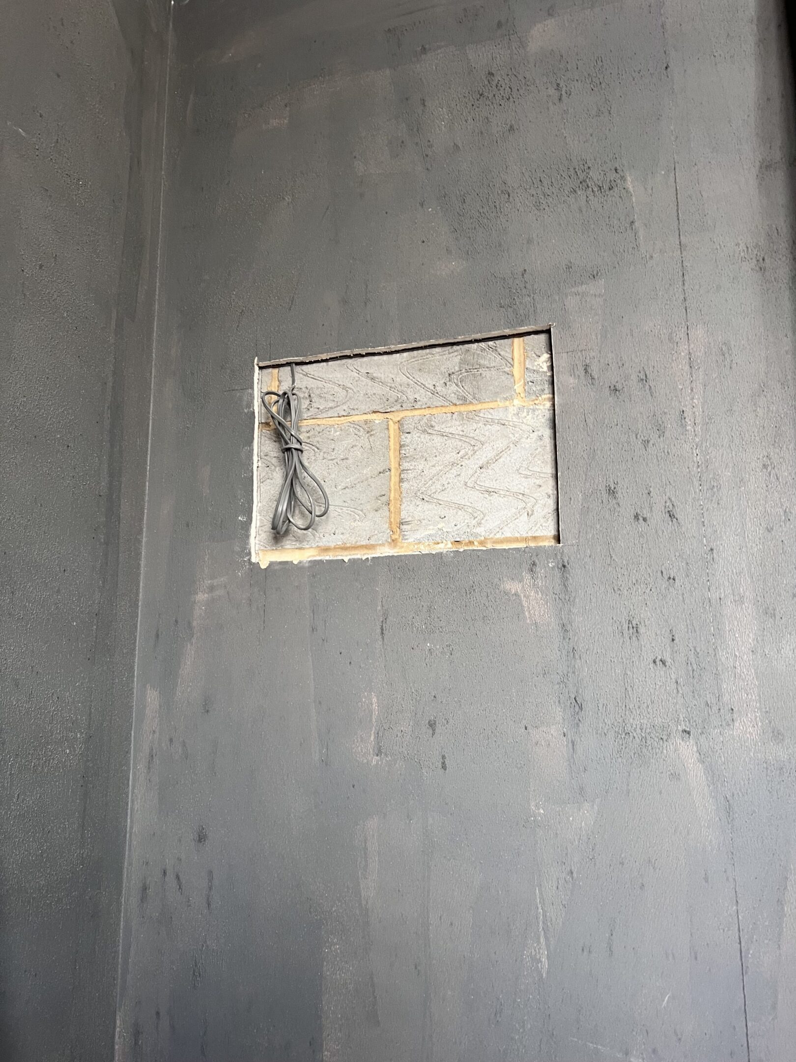 Dark gray wall with rectangular cutout and cable