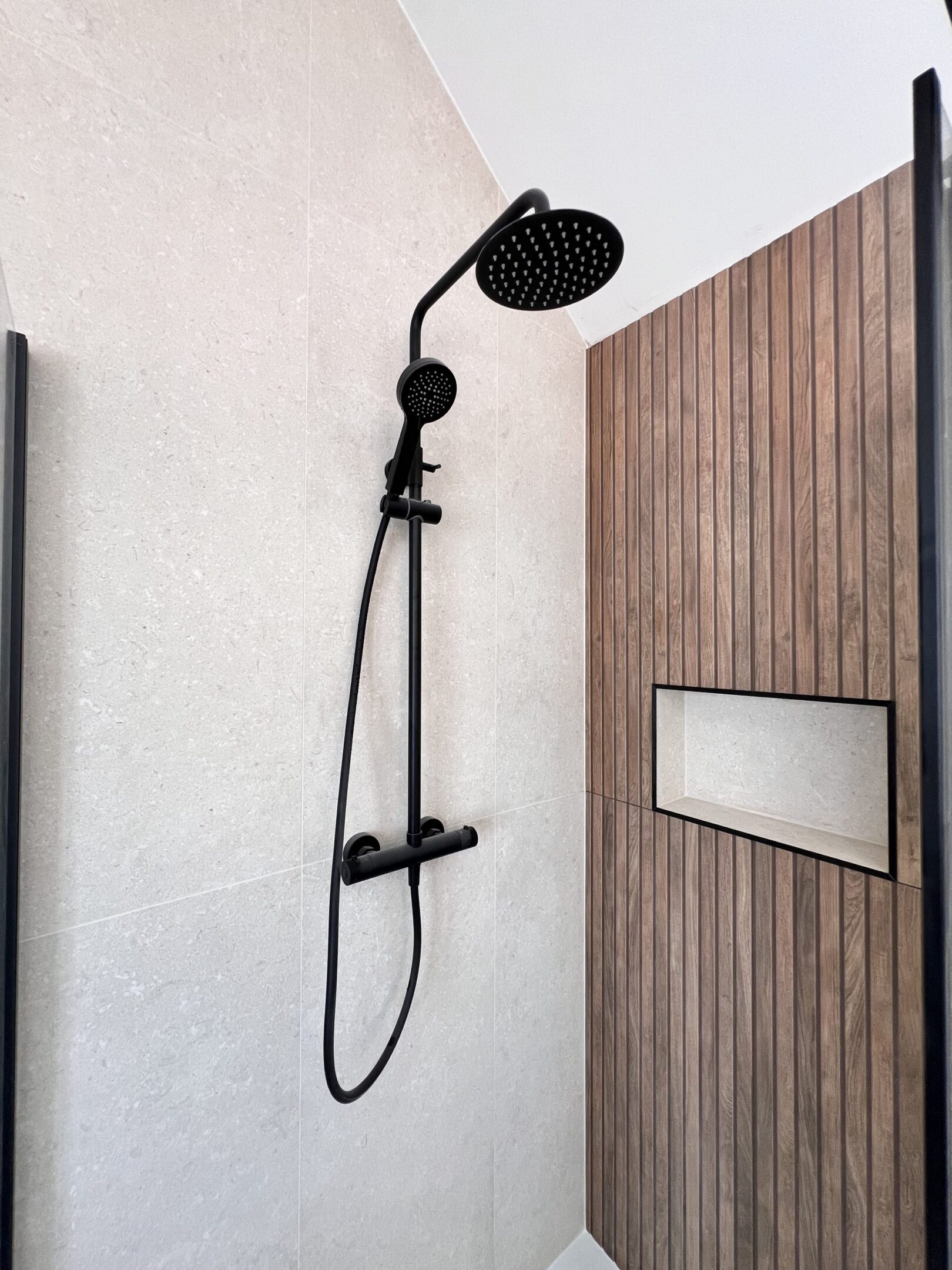 Modern black rain shower with wooden accent wall