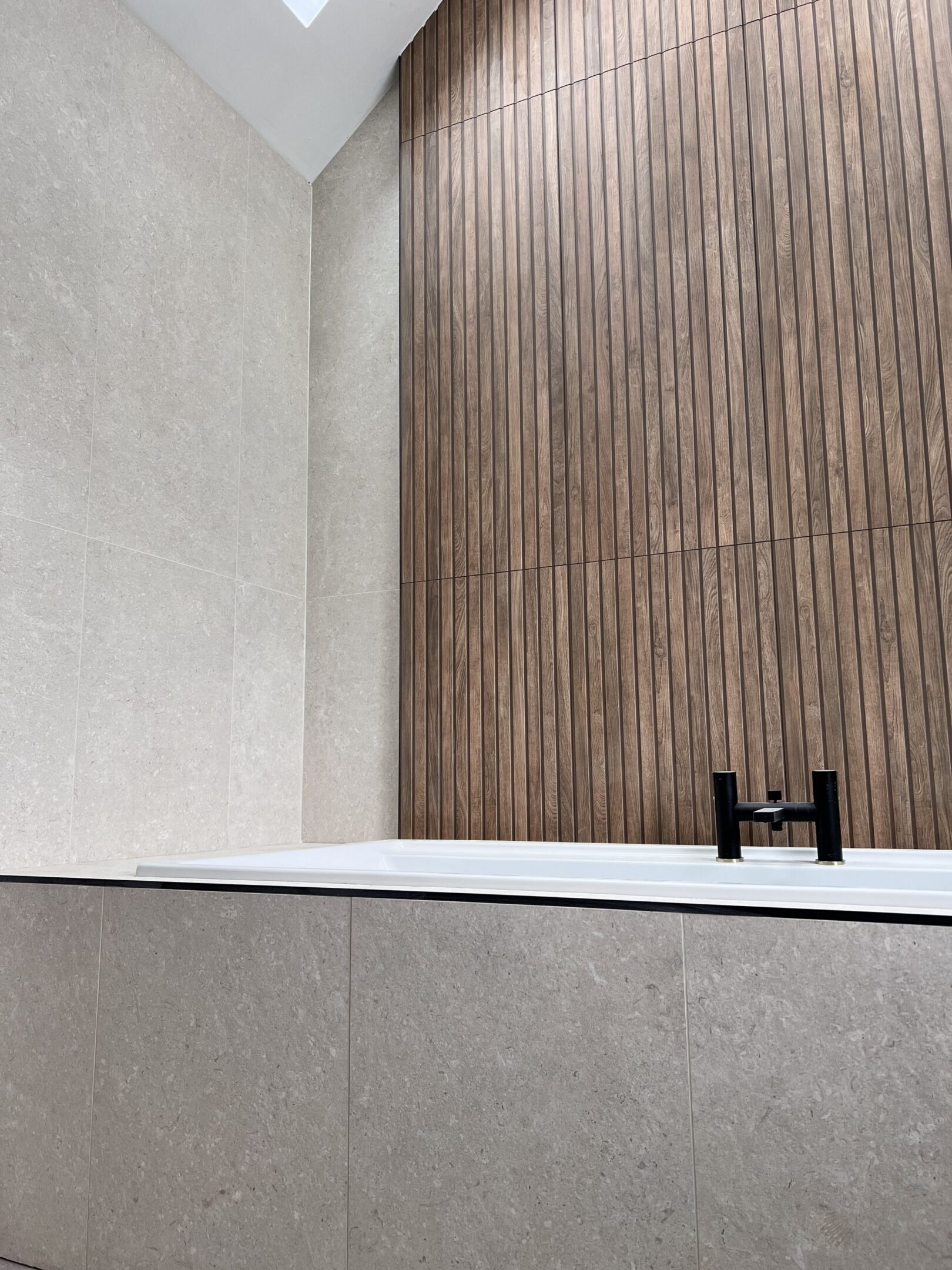 Minimalist bathtub with wood-paneled wall and faucet