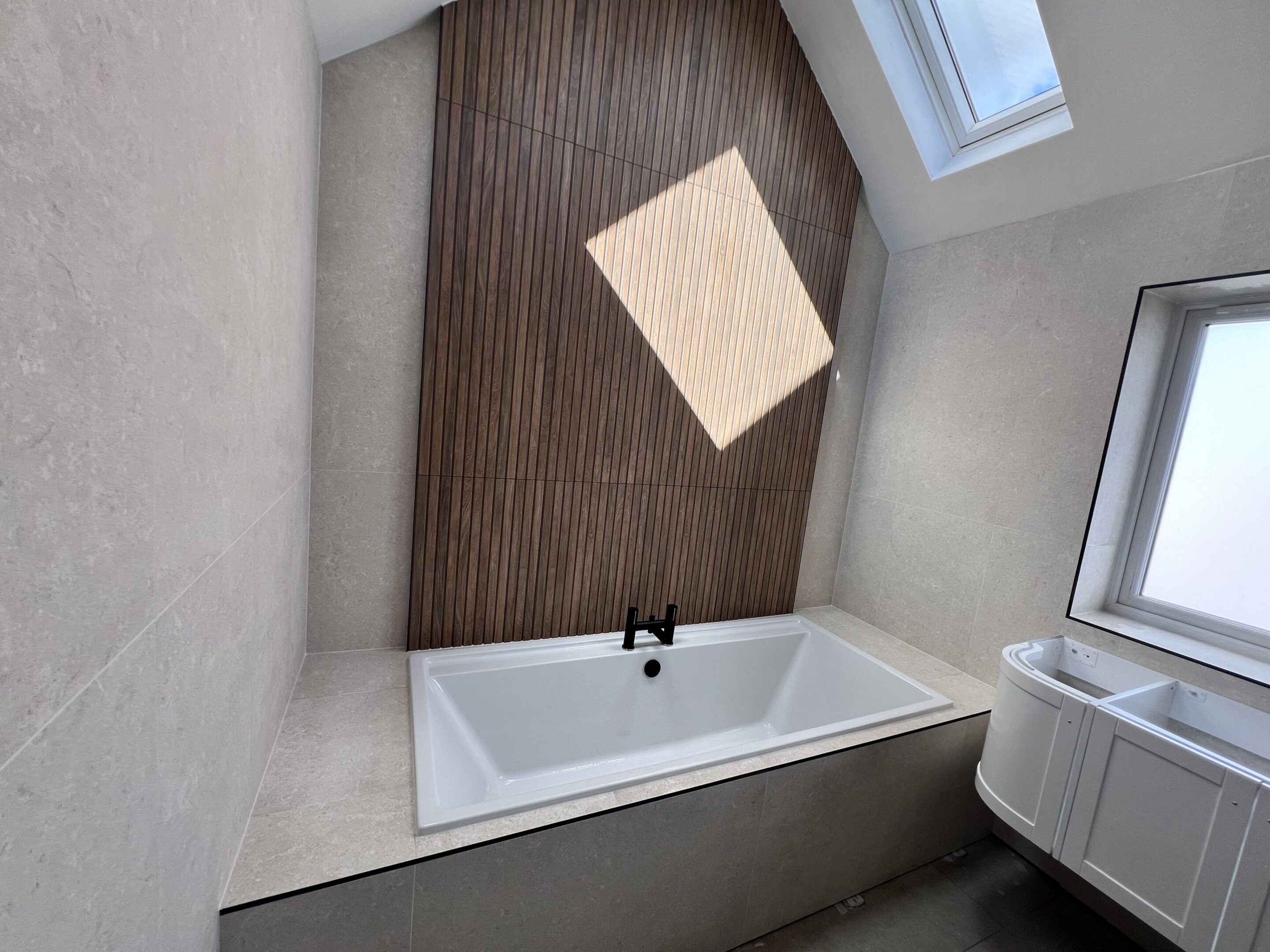 Modern bathtub with wood accent wall and skylight