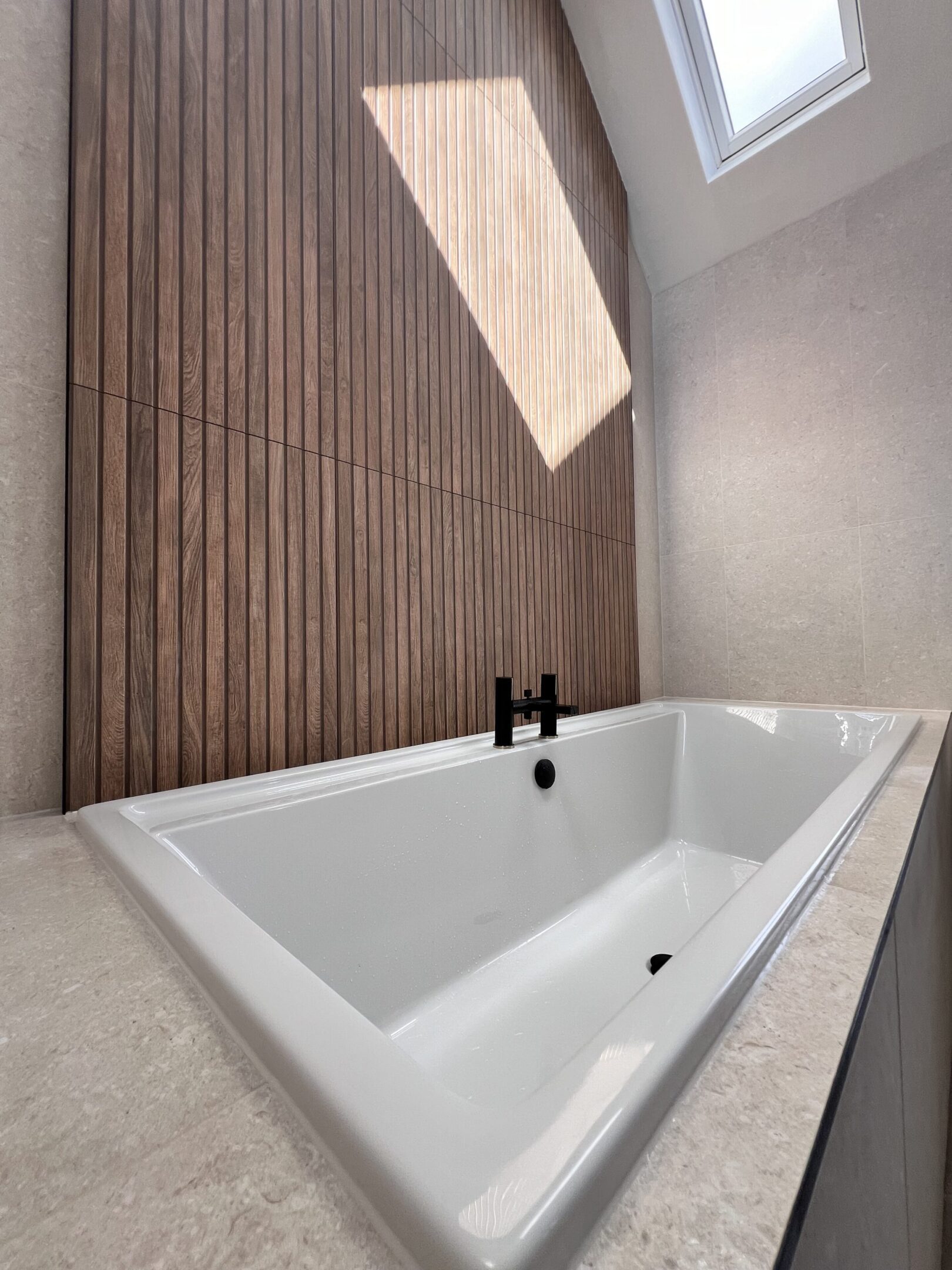 Modern bathtub with wood-paneled wall and skylight