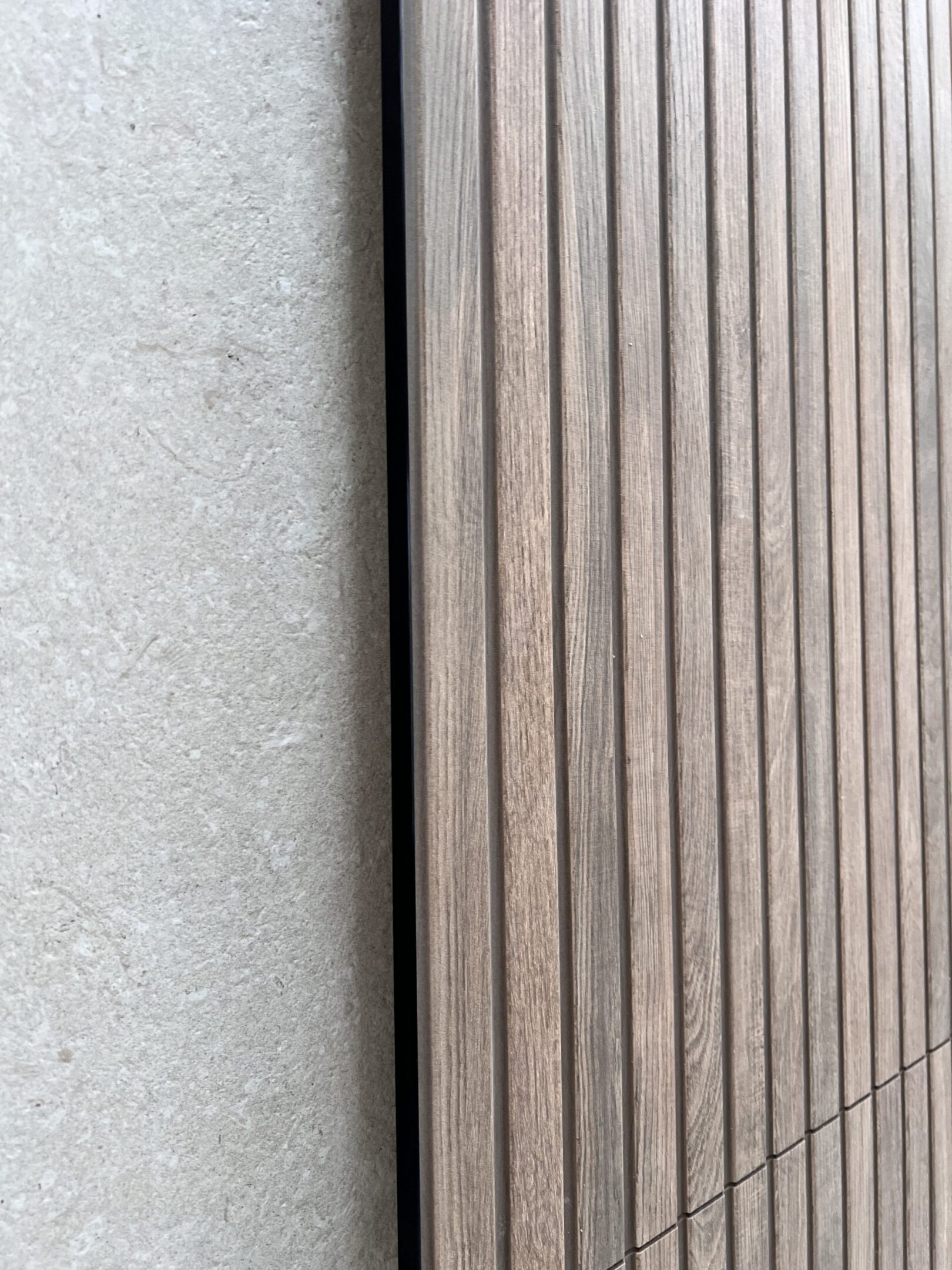 Vertical wooden slat paneling beside stone wall