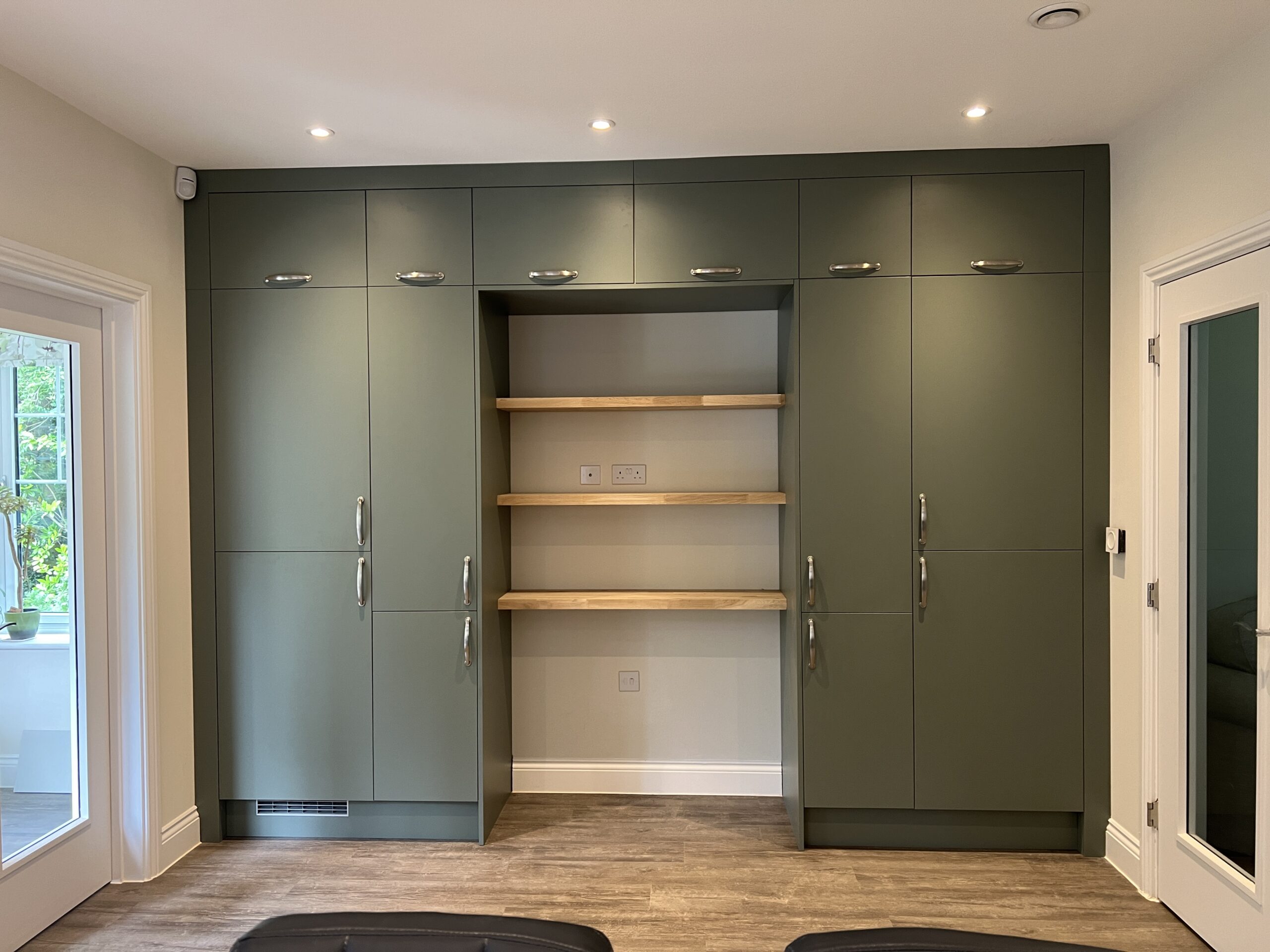 Olive green built-in cabinets with wooden shelves